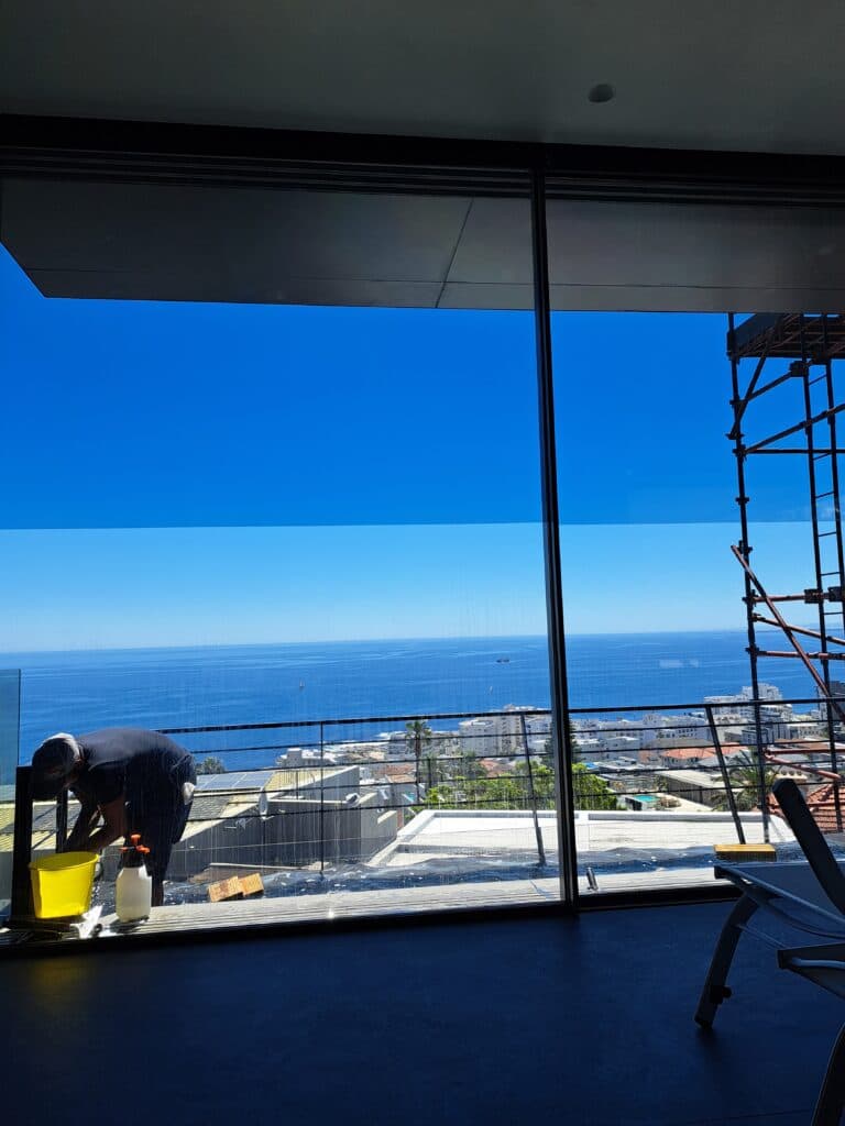 Large tinted floor-to-ceiling window overlooking ocean view after professional window tinting installation