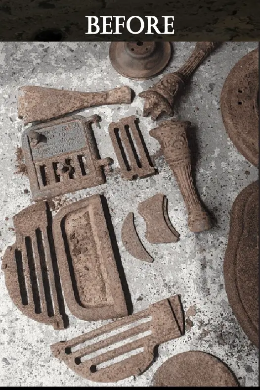 Rusty and broken antique cast iron stove parts laid out on a concrete floor before restoration